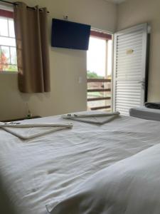 Una cama blanca con dos toallas encima. en CHILL INN HOSTEL & POUSADA CENTRO en Parati