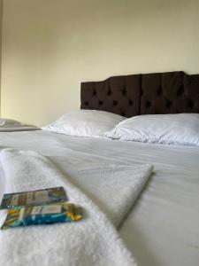 - un lit avec des draps blancs et un livre dans l'établissement CHILL INN HOSTEL & POUSADA CENTRO, à Parati