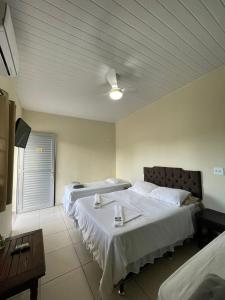 um quarto de hotel com duas camas e uma mesa em CHILL INN HOSTEL & POUSADA CENTRO em Paraty