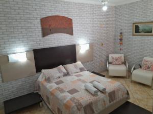 um quarto com uma cama e uma parede de tijolos em Cantinho do Paraíso em Águas de Lindoia