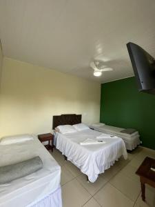 Habitación con 2 camas y pared verde. en CHILL INN HOSTEL & POUSADA CENTRO, en Paraty