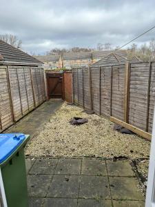 a garden with a wooden fence and a gate at Lovely Two Bedroom Flat in Thamesmead