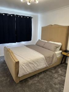 a bedroom with a large bed with black curtains at Lovely Two Bedroom Flat in Thamesmead