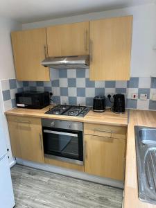 a kitchen with a stove and a sink at Lovely Two Bedroom Flat in Thamesmead