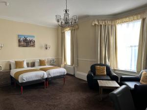 ein Schlafzimmer mit einem Bett, einem Sofa und einem Kronleuchter in der Unterkunft Clifton Hotel in Scarborough