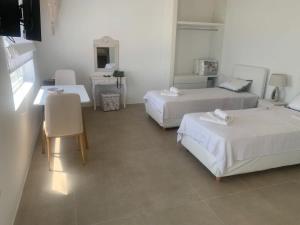 a hotel room with two beds and a table at Agean Studio with Breathtaking Views in Agios Sostis Mykonos