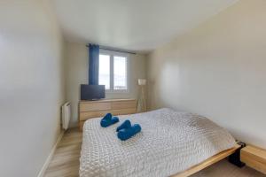 een slaapkamer met een bed met blauwe kussens erop bij Cocon Parisien in Ris-Orangis