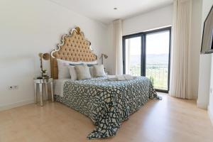 um quarto com uma cama grande e uma janela grande em Quinta da Terrincha em Torre de Moncorvo