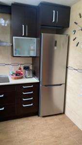 a stainless steel refrigerator in a kitchen with black cabinets at Apartamento Ginette Beach & Jacuzzi in Salou