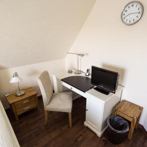 a desk with a computer and a chair and a clock at Ferienwohnung Vadrup in Westbevern
