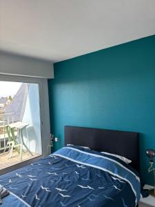 a bedroom with a blue accent wall and a bed at L'Imprenable vue mer in Crozon