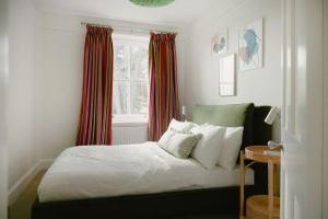 - une chambre avec un lit doté de rideaux rouges et d'une fenêtre dans l'établissement Trinity Farmhouse - Stunning House & Gardens!, à North Cerney