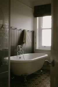 La salle de bains est pourvue d'une baignoire blanche et d'une fenêtre. dans l'établissement Trinity Farmhouse - Stunning House & Gardens!, à North Cerney