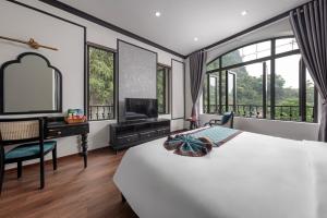 a bedroom with a bed and a desk with a television at Indochine Boutique Hotel Ninh Bình in Ninh Binh