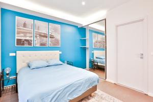 um quarto com paredes azuis e uma cama branca em Blue Nights Apartments - Sébastopol em Paris