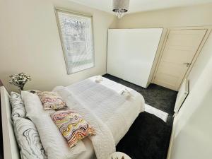 een slaapkamer met een bed met witte lakens en kussens bij Glasgow Modern style home , separate entrance in Knightswood