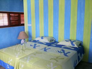 a bedroom with a bed with blue and yellow stripes at Villa Los Gorgones in Las Galeras