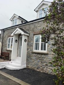 a stone house with a white door and windows at Efail Fach in New Quay