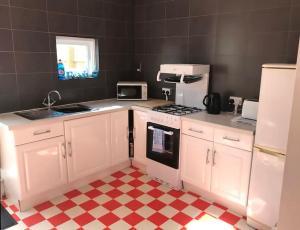 a kitchen with white appliances and a checkered floor at Aule Apartment in Bembridge