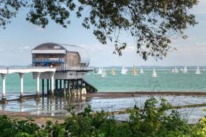 a building on the beach with sailboats in the water at Aule Apartment in Bembridge