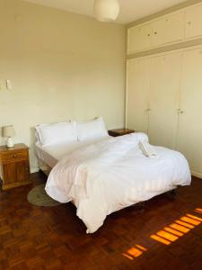 a bedroom with a large bed with white sheets at Januario Maputo in Maputo