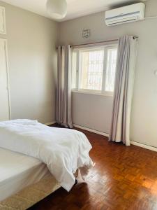 ein Schlafzimmer mit einem weißen Bett und einem Fenster in der Unterkunft Januario Maputo in Maputo