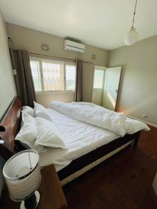 a bedroom with a large bed with white sheets and pillows at Januario Maputo in Maputo