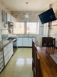 a kitchen with white cabinets and a wooden table at Januario Maputo in Maputo