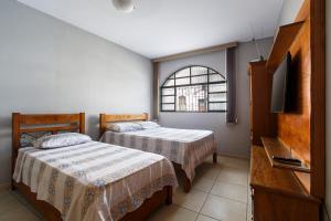 a bedroom with two beds and a tv and a window at Aconchego São Francisco, Casa 100m Igreja São Francisco, Pet friendy in São João del Rei