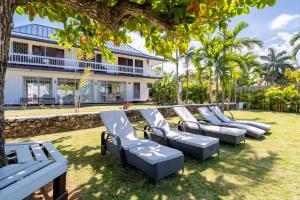 a row of chaise lounge chairs in front of a house at Villa Turrasann in Runaway Bay