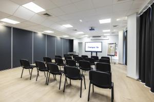 uma sala de conferências com cadeiras e um ecrã de projecção em Campanile Perpignan Aéroport em Rivesaltes