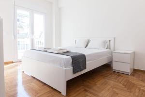 1 cama blanca en un dormitorio blanco con suelo de madera en Stylish New Paradise Apt for 2 in Marousi, en Atenas