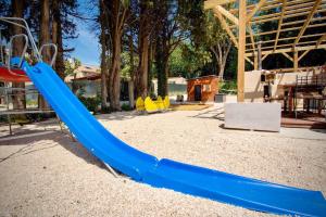 une aire de jeux avec un toboggan bleu dans un parc dans l'établissement Appartement d'une chambre avec piscine partagee jacuzzi et jardin clos a Avignon, à Avignon