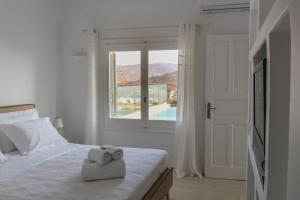 een slaapkamer met een bed met twee handdoeken erop bij Luxury White Oasis Villa w Private Pool in Mikonos in Kalafatis