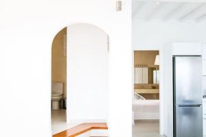 - une cuisine blanche avec un réfrigérateur et une baignoire dans l'établissement Luxury White Oasis Villa w Private Pool in Mikonos, à Kalafatis