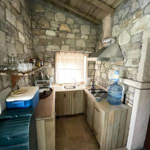 uma cozinha em pedra com um lavatório e uma janela em Saklı Doğa Çiftlik Hayatı Taş Ev em Urla