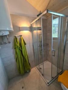 ein Bad mit einer Dusche und grünen Handtüchern in der Unterkunft Ferienhaus Woodcube Großkirchheim in Großkirchheim