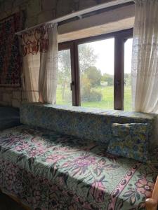 Bett in einem Zimmer mit einem großen Fenster in der Unterkunft Saklı Doğa Çiftlik Hayatı Taş Ev in Urla