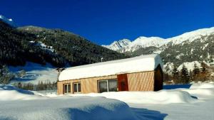 um pequeno edifício na neve com montanhas ao fundo em Ferienhaus Woodcube Großkirchheim em Grosskirchheim