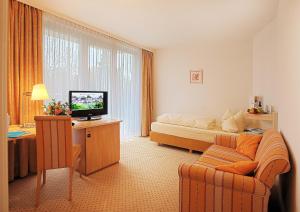a hotel room with a bed and a couch and a television at Hotel Sonnengarten in Bad Wörishofen