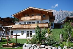 a large house with a wooden roof with a yard at Appartment Scheiber in Leogang