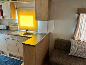 a small kitchen with a sink and a couch at 6 Berth Caravan At Dovercourt Holiday Park In Essex Ref 44006s in Great Oakley