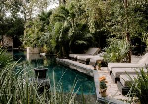 a backyard with a pool with couches and trees at Hotel Bardo - Adults Only in Tulum