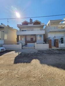 a large house with the sun shining behind it at Surf House in Artemida