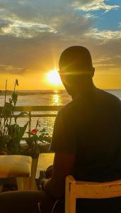 Ein Mann, der auf einer Bank sitzt und den Sonnenuntergang beobachtet. in der Unterkunft Teranga Lebou in Dakar
