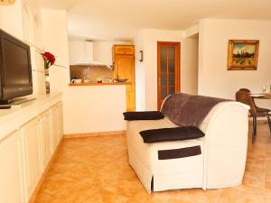 uma sala de estar com um sofá branco e uma televisão em Bas de villa avec Piscine et Terrasse au calme em Contes