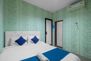 ein Schlafzimmer mit einem großen weißen Bett mit blauen Kissen in der Unterkunft HOUSE MUSE in Siantan