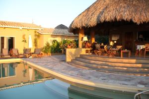 a resort with a swimming pool and a thatch roof at Hotel Casa Pan de Miel (Only Adults) in Mazunte