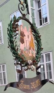 a sign hanging from a building with a painting on it at Haus zum Rütli in Chur