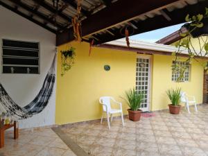 a patio with white chairs and a yellow wall at Cantinho do Paraíso in Águas de Lindóia